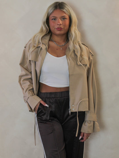 Model wearing a spring, tan, trench coat with brown pants 