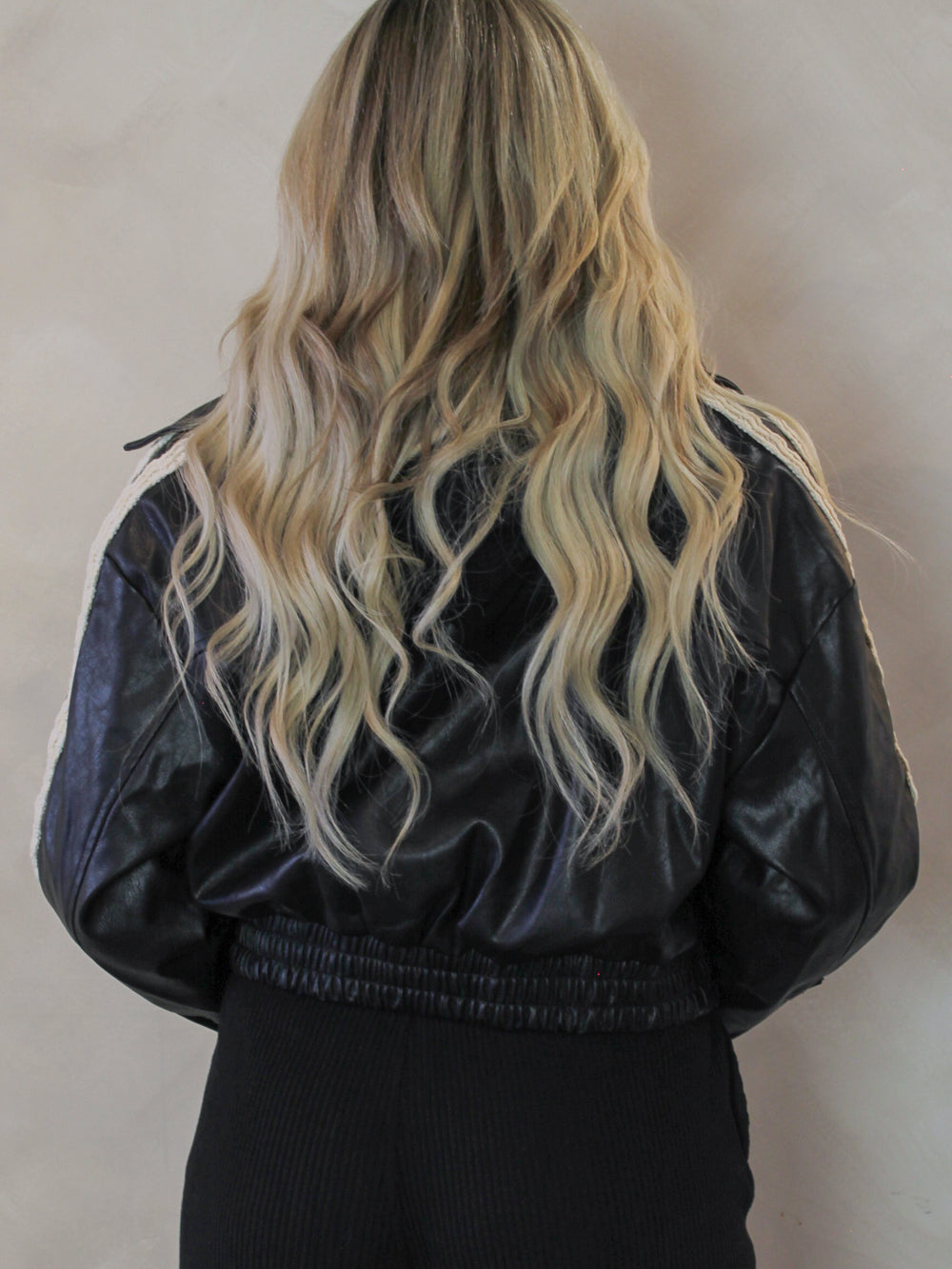 Back view of a black leather bomber jacket on a model 