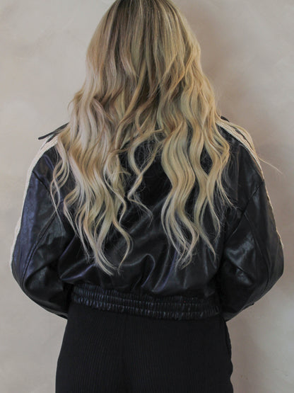 Back view of a black leather bomber jacket on a model 