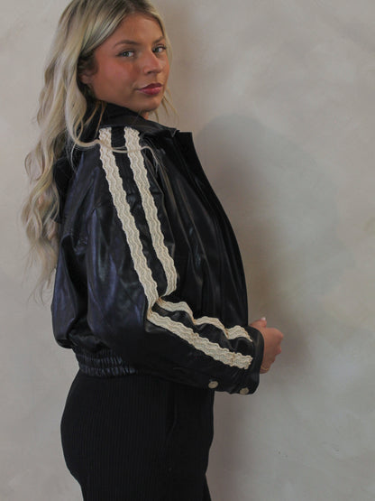 Model wearing a black, leather bomber with white lace trim detail 