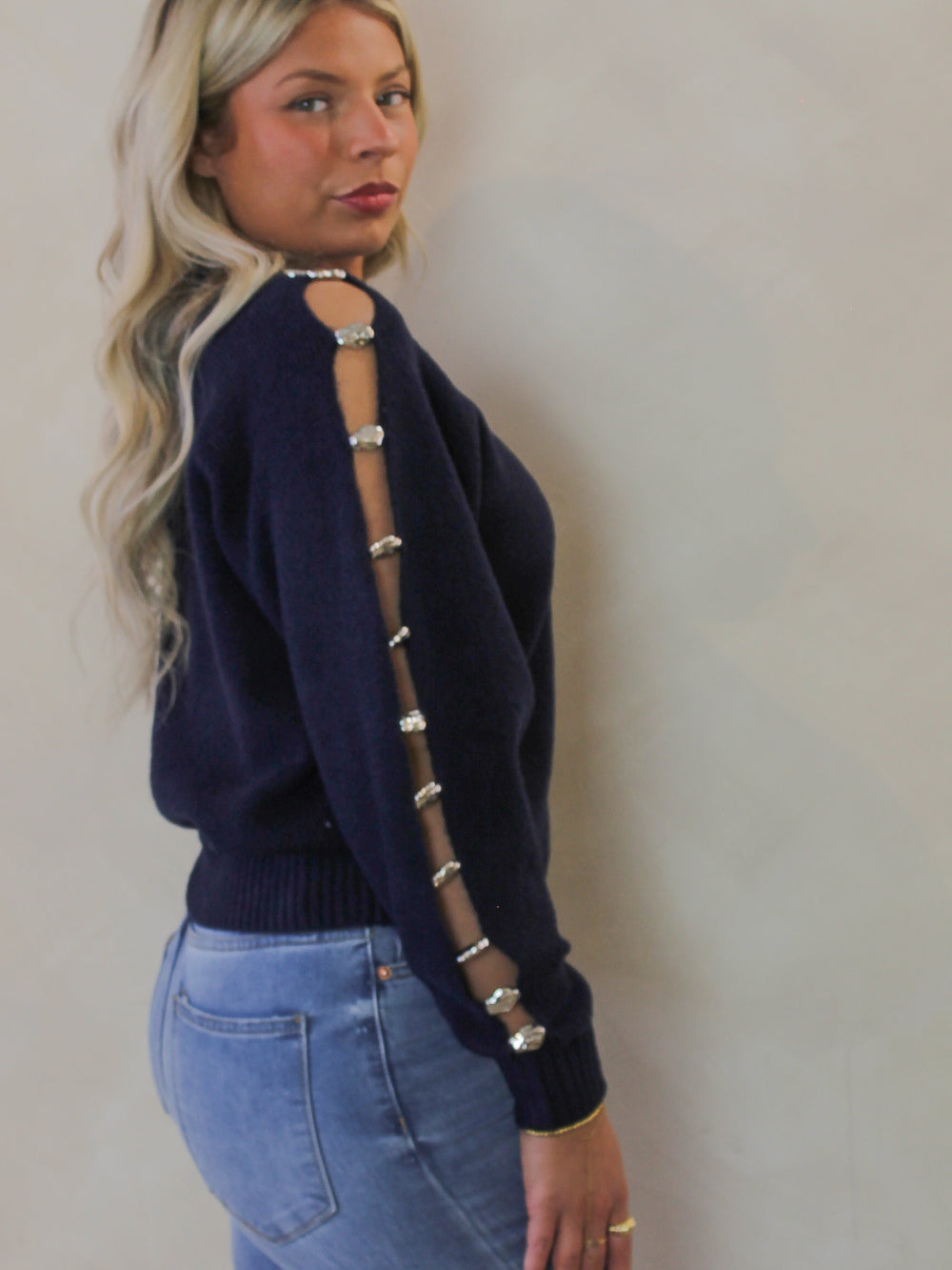 Model wearing a navy blue sweater with silver stone details 