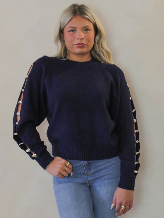 Model wearing a navy blue sweater with an open arm detail 