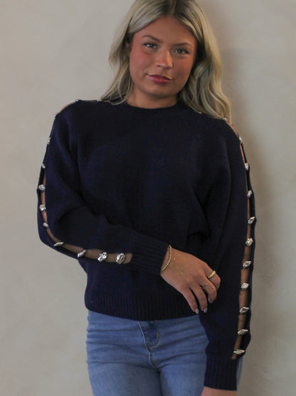Model wearing a navy blue sweater with open slit details in the arm 