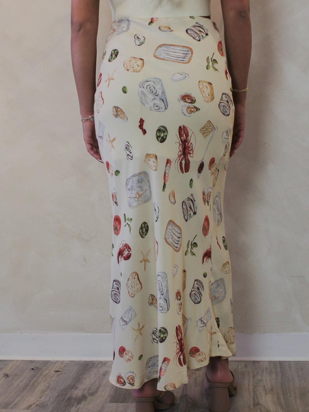 Back view of a model wearing a neutral, coastal printed maxi skirt