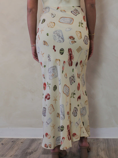 Back view of a model wearing a neutral, coastal printed maxi skirt