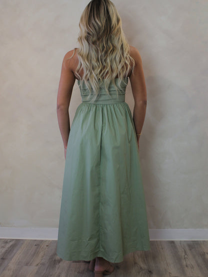 Back view of a model wearing a sage green, spring dress